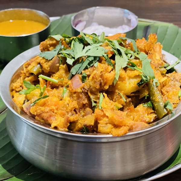 Kuppanna's South Indian Kothu Parotta, a shredded flatbread dish, garnished with fresh cilantro and served with two dipping sauces.